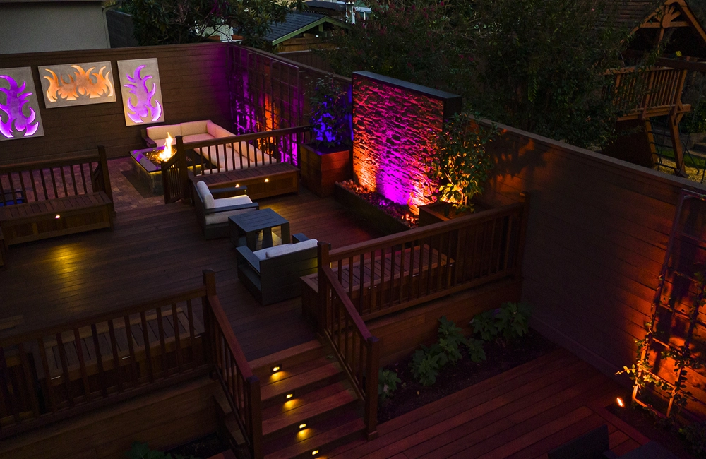 Outdoor living area with architectural uplighting illuminating patio walls, deck spaces, and evening entertainment areas.
