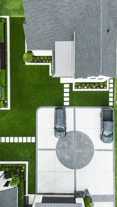 Aerial view of a modern residential landscape design with geometric walkways, manicured lawn, and structured planting beds.