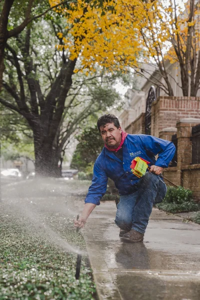 Professional irrigation system maintenance by Hogue Landscape Services technician working on residential sprinklers.
